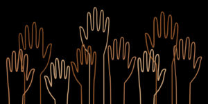 Raised hands in different shades of brown on black background