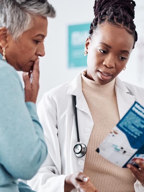 Doctor talking to patient for healthcare services, looking at brochure. 